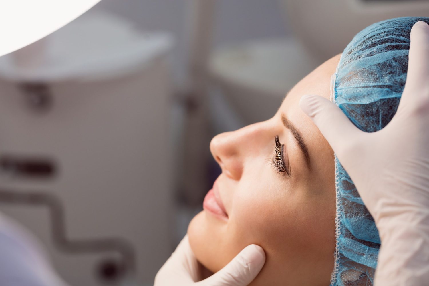 Hands of doctor examining womans face for cosmetic treatment at clinic